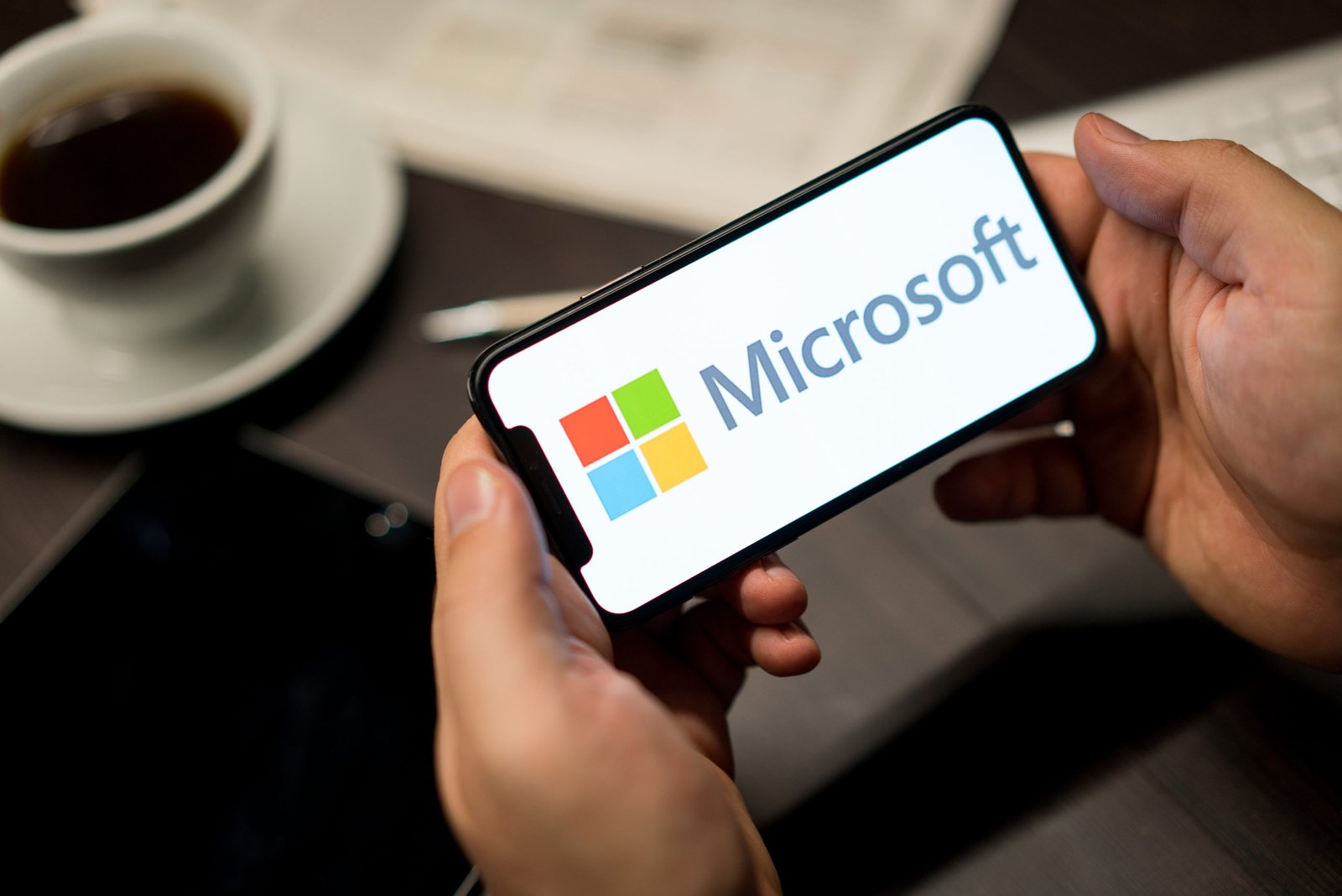 A hand holding a phone with a Microsoft licensing logo